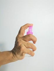A photograph of an old hand pressing an alcohol injection from a portable bottle. White background.