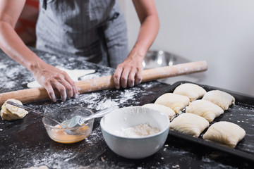 Fototapeta premium Young woman rolling dough with long pin for samsa cooking at home.