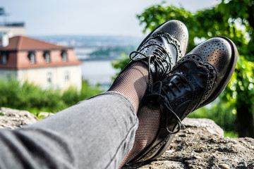 Black silver woman brogue shoes on a rock wall
