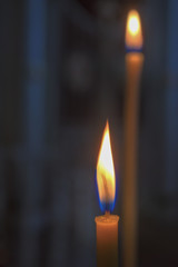 Two hot candles standing on a dark background.