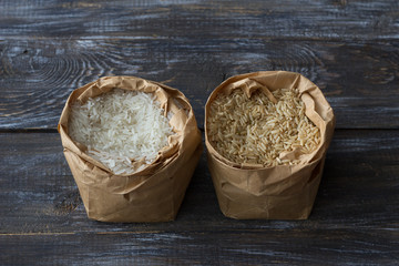 Raw long-grain brown and white basmati rice in a paper craft bags on a wooden background, space