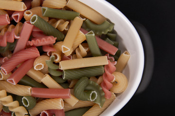A white ceramic bowl of colorful pasta.