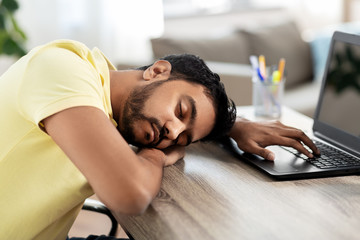 people and lifestyle concept - tired indian man sleeping on table with laptop computer at home