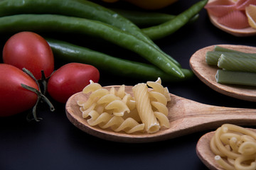 A spoon of fusilli pasta and some spices.