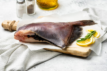 Raw Dory fish on a wooden Board on the light gray kitchen table. Dory fish close up