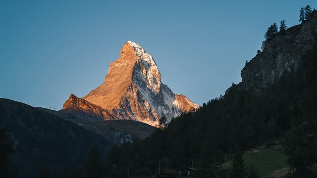 Time lapse of early morning golden sunlight slowly covering the Matterhorn mountain peak in the alps of Switzerland at sunrise