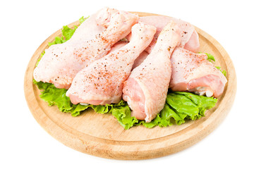 Raw chicken legs on wooden plate isolated on white background