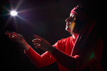 Portrait of middle age woman in red sweater and the turban of wizard or sorcerer on black...