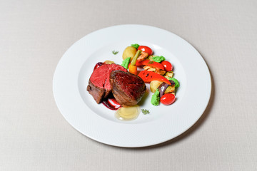 Meat steak with vegetables on a white plate