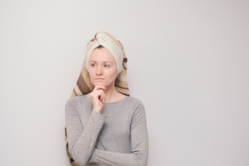 Young girl with a towel on her head. Happy and smiling woman on a grey background.