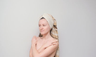Young girl with a towel on her head. Happy and smiling woman on a grey background.