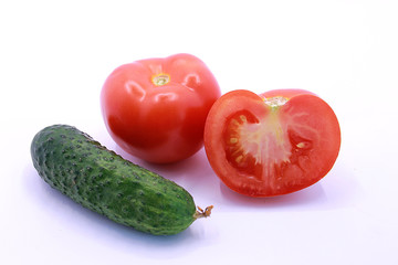 Photo of young cucumbers and tomato on a white background, close-up