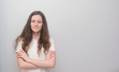 Young and beautiful girl wearing white T-shirt on grey background.