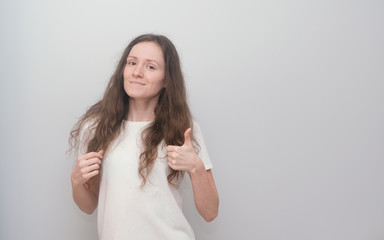 Young and beautiful girl wearing white T-shirt on grey background.