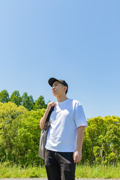 エコバックを持って買い物をする日本人男性。青空背景