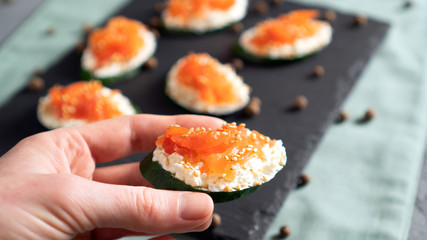 Cucumber with cream cheese and salmon in the hand. Concept of healthy sandwich alternative. Ready to eat.