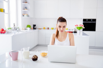Photo of domestic charming house wife lady sitting morning kitchen browsing notebook freelancer drink tea milk have breakfast staying home distance remote work quarantine time indoors