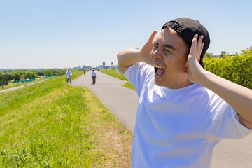 耳を抑える日本人男性。青空背景