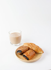Croissant chocolate and butter on wooden with glass of milk tea on white background   