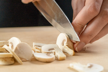 women's hands cut mushrooms on a wooden board close up