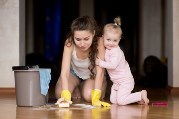 Mom washes the floor, and the little daughter hugs mom