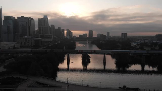 A drone flies over the Colorado River and Ladybird Lake  in Austin, Texas at the Lamar Street Bridge capturing morning workouts of a rowing crew team.