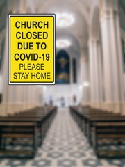 ''Church closed due to COVID-19. Please stay home'' information sign against a defocused church interior