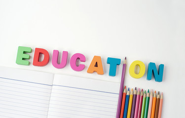 " EDUCATION " Multicolored Wooden Letters with Color Pencil Instead ' I ' Letter and Paper Book on White Background, Learning knowledge 