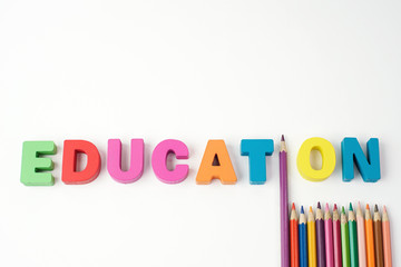 Multicolored Wooden Letters " EDUCATION " with Multicolored Pencil on White Background, Copy Space