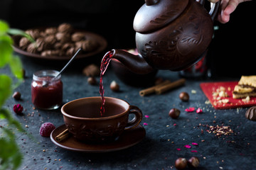 Pink tea is poured into a mug from the teapot. Red tea is poured from above. Female hand dares...