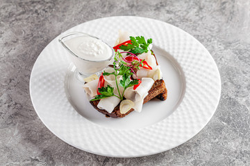 Ukrainian cuisine in the European style. Salted fat on black bread Snack for borscht soup. Beautiful serving dish in a restaurant on a white plate. background image copy space text