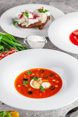 Ukrainian cuisine in European style. Solyanka soup with assorted sausages and meat. Beautiful serving dish in a restaurant in a white plate. background image, copy space text