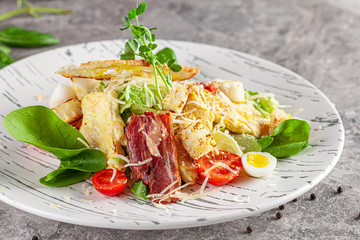 Italian Cuisine. Caesar salad with chicken, bacon, quail eggs, bread croutons, cherry tomatoes. Dish in a restaurant on a white plate. background image, copy space text