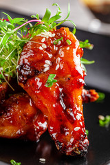 American cuisine. Juicy fried chicken wings glazed with sesame seeds and herbs. Beautiful serving dish in a restaurant in a black plate. background image, copy space text