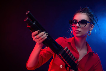 a bright brunette in a red jumpsuit with a shotgun on a dark background in neon light