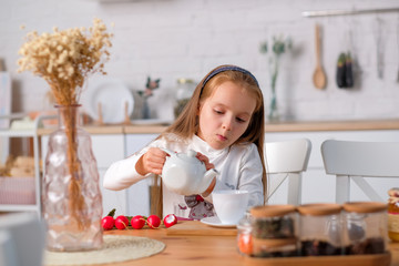 A child plays in the kitchen and pours tea