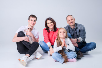 family plays with a dog on a light background on the floor