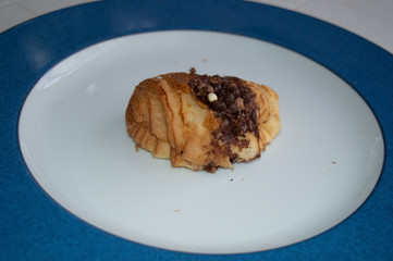 .Chocolate chips croissant on white and blue plate.A braid with chocolate .Swiss Brioche with Chocolate Chips (Brioches suisses). .