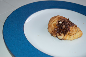 .Chocolate chips croissant on white and blue plate.A braid with chocolate .Swiss Brioche with Chocolate Chips (Brioches suisses). .