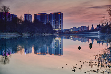 Izmailovo hotel is reflecting in water of Silver-Grape pond, Izmailovo park, Moscow during sunset. Smoke under water. Izmailovo Kremlin. Ancient russian and modern architecture side by side. 