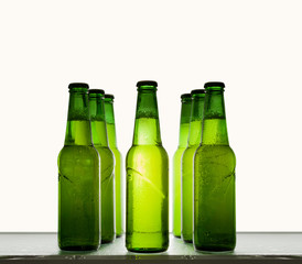 Green beer bottles chilled in water drops on a shelf on a light background.