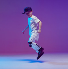 Cool young boy child dancing hip hop in the Studio against the background of neon lights. Break...