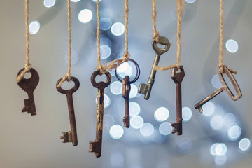 Old rusty keys hanged on the ropes with blurred lights background