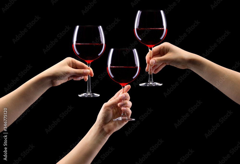 Wall mural set of hands holding red wine glass isolated on black.