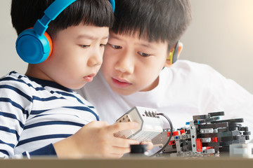 Social distancing & Learning activities, Two Asian brothers boys with headphone assemble and test a robot with EV3 components as school project at home due to school closed and Covid-19 pandemic