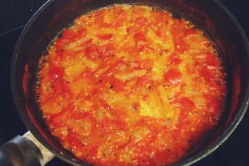 Preparación de salsa de tomate cherry. Salsa recién hecha reposando en la sartén. Tomate, cebolla y orégano fritos en aceite de oliva. Cocina española. Cocina mediterránea.