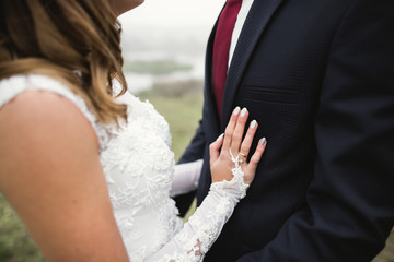 Romantic, fairytale, happy newlywed couple hugging and kissing in a park, trees in background
