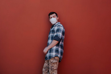 a masked man is leaning against a red wall