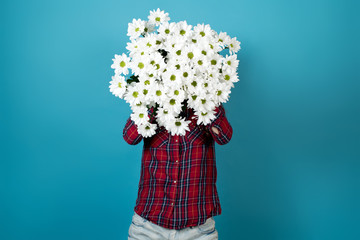 A girl in a red shirt holds in front of him a bouquet of white chrysanthemums