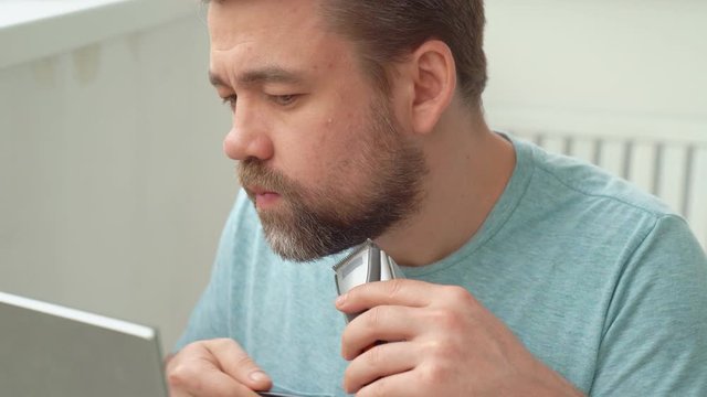 Man makes haircut of beard razor at home.